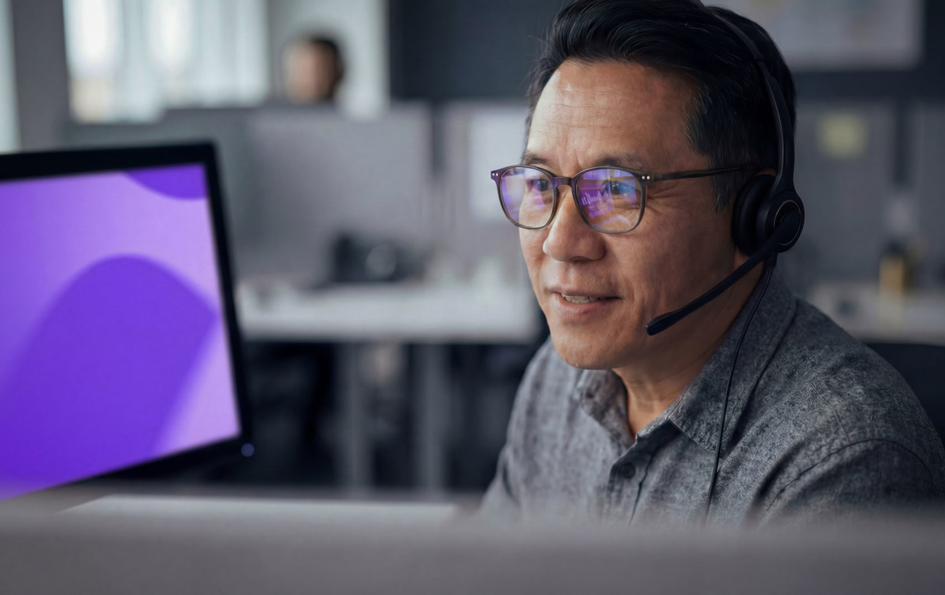 Ein Mann mit Headset, im Hintergrund ein Bildschirm