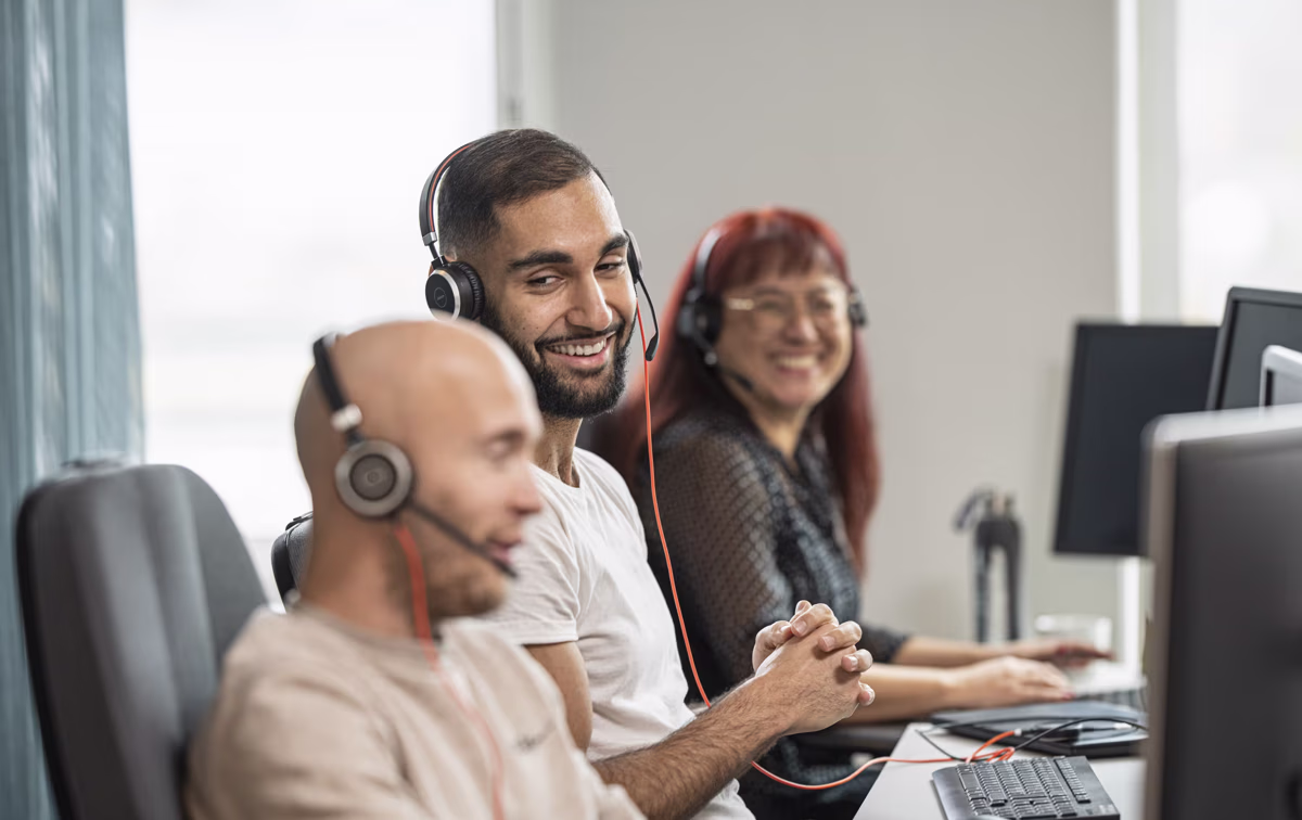 Drei Personen aus dem Call CEnter sitzen nebeneinander und unterhalten sich